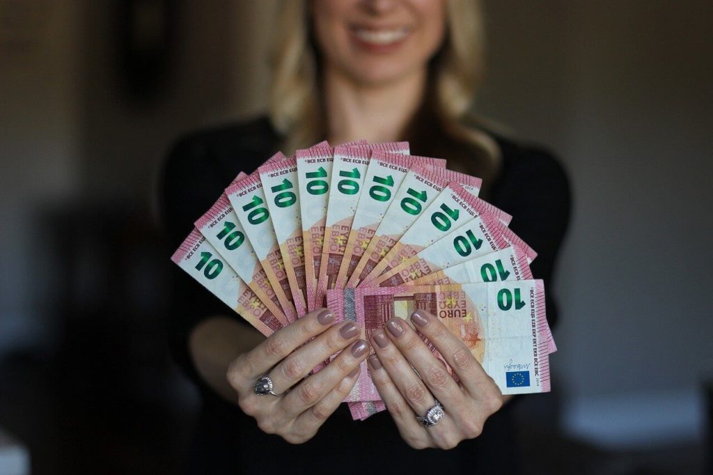 На фото женщина держит в руках деньги веером.