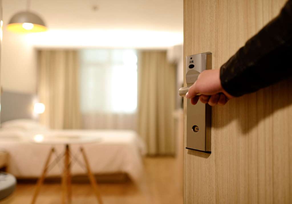 На фото человек открывает дверь в номер в отеле.